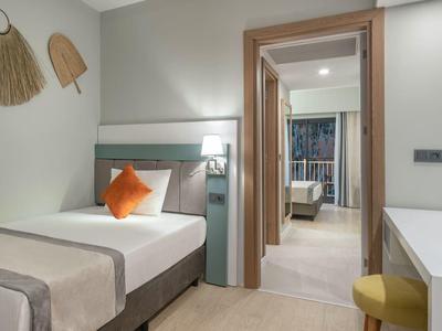 Modernes, gemütliches Einzelzimmer mit hellem Holz, weißer Wand und orangefarbener Kissenakzent.