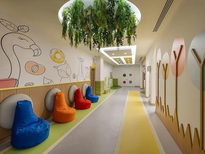 Moderner Kindergartenraum mit bunten Sitzsäcken, Wandmalerei und Pflanzen von der Decke.