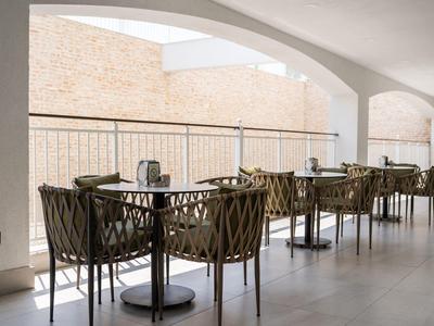 Moderner Außenbereich mit eleganten Tischen und Stühlen unter großen Bogenfenstern.