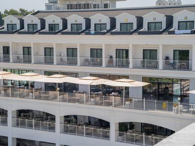 Modernes Hotel mit Balkonen, Terrassen und Sonnenschirmen in hellem Design.