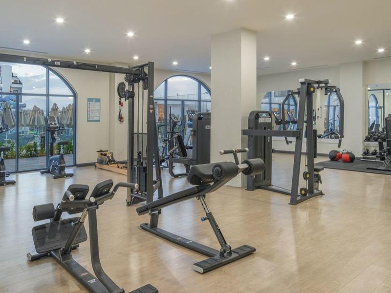 Ein heller, weitläufiger Fitnessraum mit verschiedenen Trainingsgeräten und großen Fenstern.