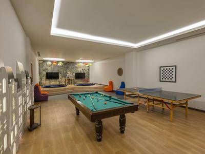 Sala gioco con tavolo da biliardo, tavolo da ping-pong e sedute in ambiente moderno.