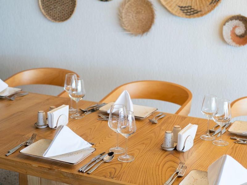 Nakryty drewniany stół z białymi serwetkami i sztućcami w restauracji z dekoracjami ze wzorem z wikliny na ścianie.