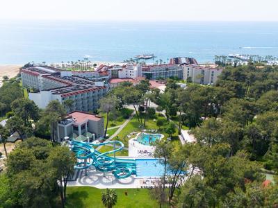 Widok na ośrodek hotelowy z wieloma basenami, zjeżdżalniami wodnymi i zielonym otoczeniem nad morzem.