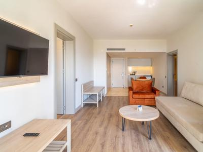 Nowoczesny pokój hotelowy z sofą, telewizorem i stolikiem na drewnianej podłodze.