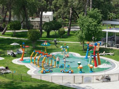 Plac zabaw wodnych dla dzieci z kolorowymi urządzeniami w ogrodzie z leżakami