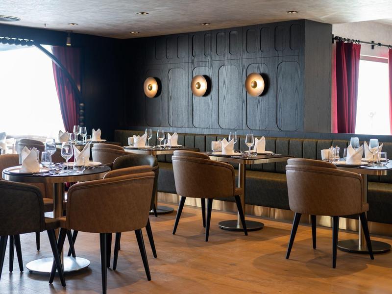 Nowoczesna restauracja z drewnianą podłogą, skórzanymi krzesłami i artystycznie ozdobioną ścianą