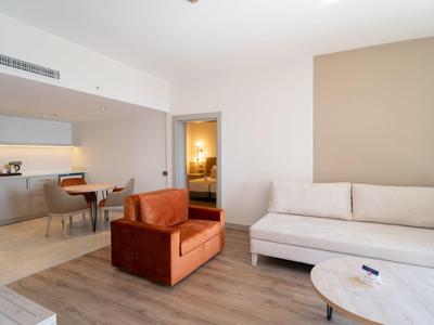 Salon moderne avec mobilier beige et marron et vue sur la cuisine.