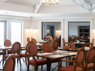 Salle à manger élégante avec tables en bois et chaises rembourrées dans des tons chauds.