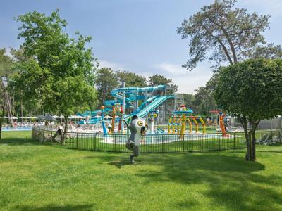 Aire de jeux aquatique avec toboggans et balançoires entourée de pelouse verte et d'arbres