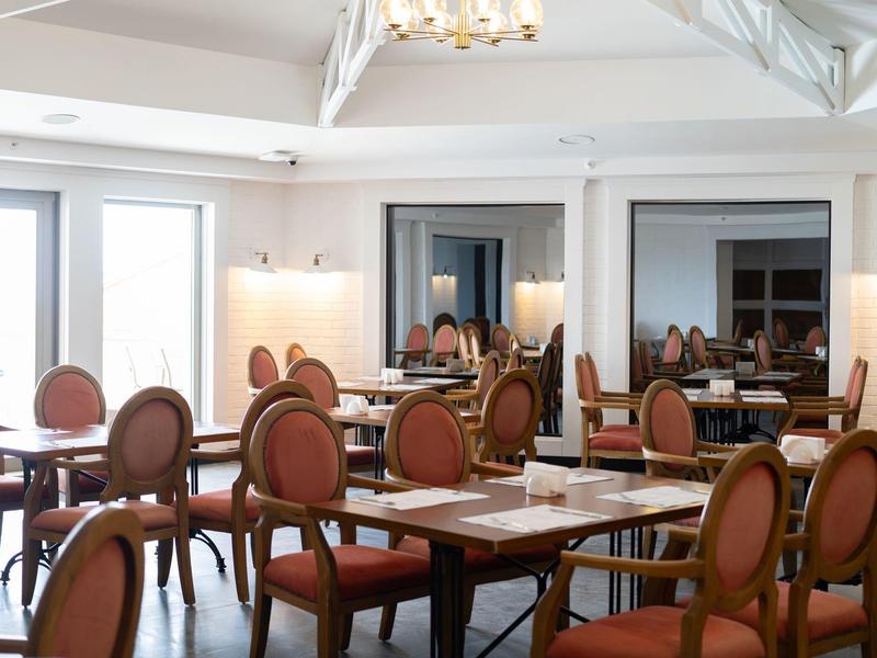 Salle à manger élégante avec tables en bois et chaises rembourrées dans des tons chauds.