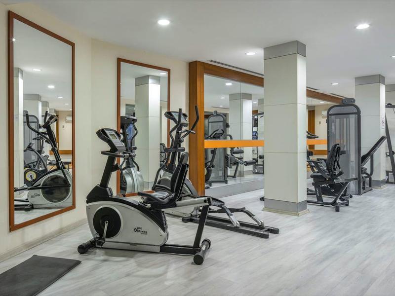 Salle de sport moderne avec miroirs, appareils de cardio et banc de musculation dans une pièce lumineuse.
