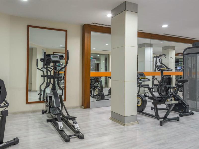 Salle de sport moderne avec divers équipements d'exercice et grands miroirs aux murs.