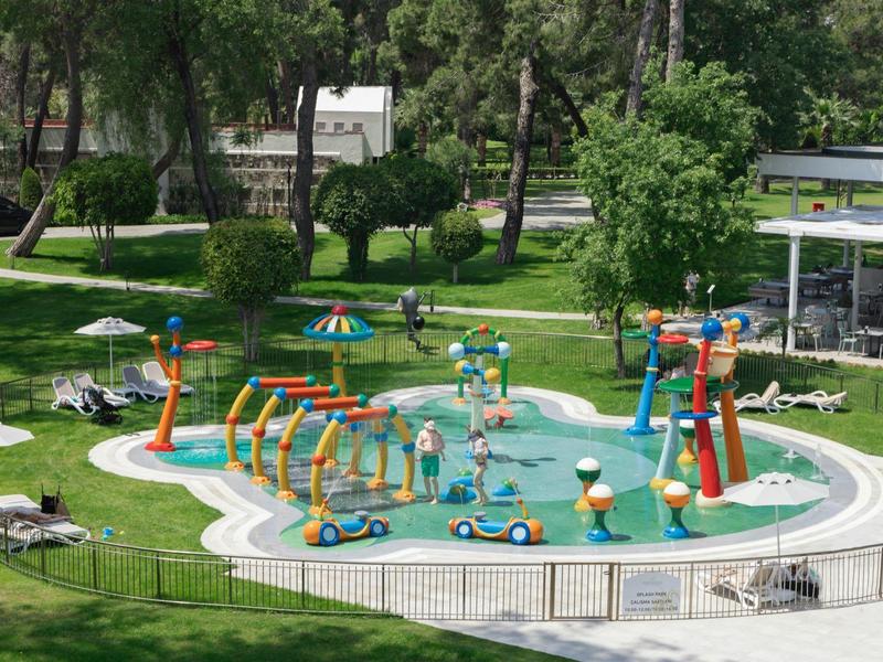 Aire de jeux d'eau colorée pour enfants dans un jardin avec chaises longues