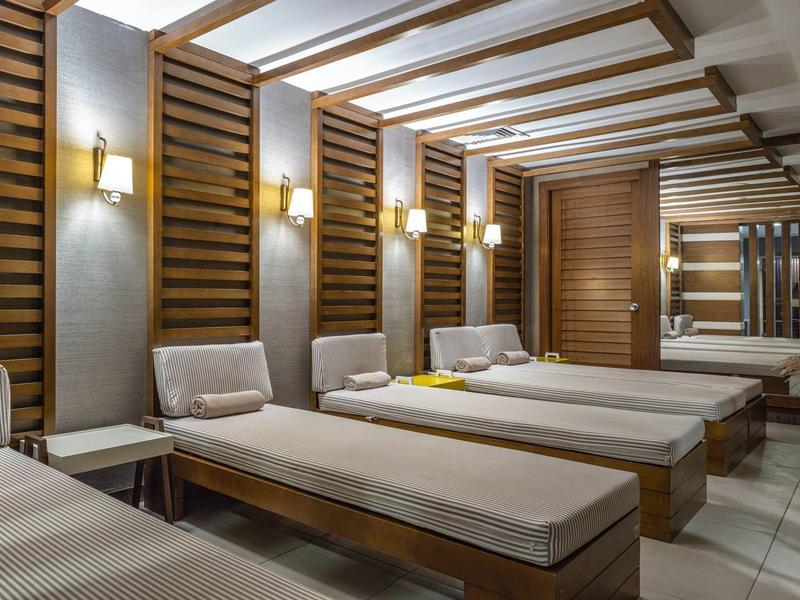 Salle de détente moderne avec chaises longues, éclairage chaud et panneaux en bois dans un hôtel bien-être.