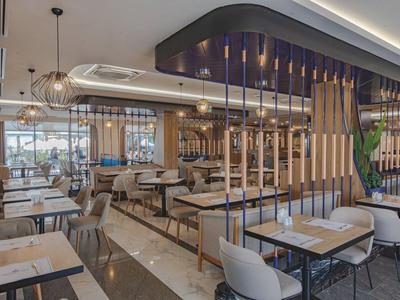 Modern bright restaurant with white tables, gray chairs, and decorative wooden slats.