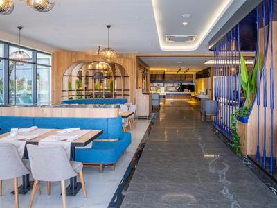 Modern restaurant with blue benches, white chairs, and large windows with a view.