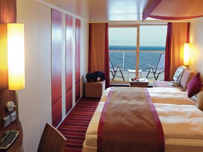 Modern hotel room with two beds and balcony overlooking the sea.