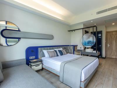 Moderna habitación de hotel con cama grande, sofá gris y decoración azul elegante.