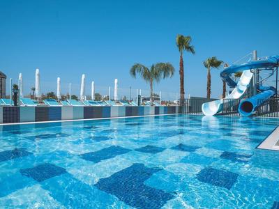 Piscina dell'hotel con sgabelli sommersi, ombrelloni e lettini sotto il sole.