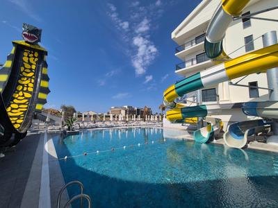 Vista su una piscina clorata con scivoli d'acqua e sole in un hotel.