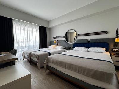 Camera d'hotel con due letti, una grande finestra e arredamento moderno in toni neutri.