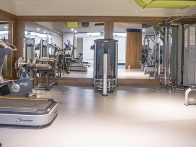 Spacious hotel gym with treadmills, strength machines, and mirrors on the walls.