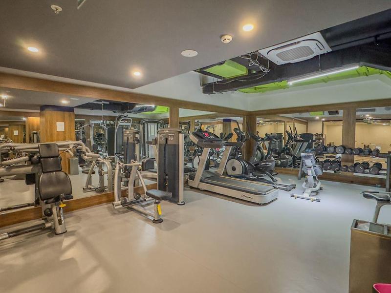 Ampia palestra con varie attrezzature moderne e specchi alle pareti.