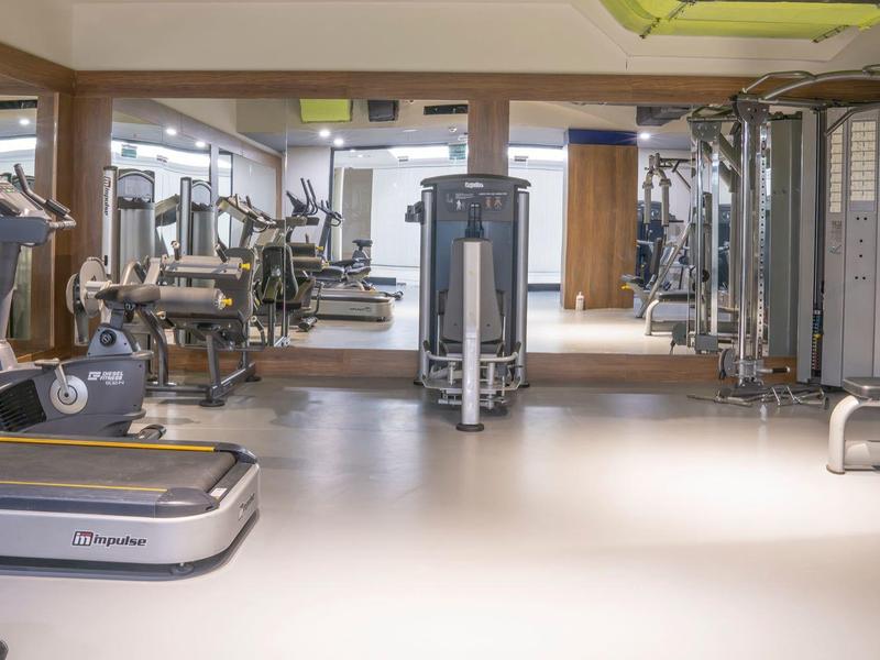 Palestra moderna con attrezzi da allenamento e specchi in un ambiente luminoso.