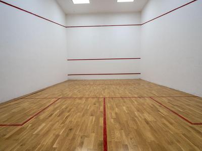 Wnętrze kortu do squash z drewnianą podłogą i czerwonymi liniami.