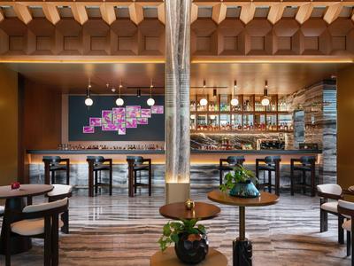 Nowoczesny hotelowy bar z drewnianymi meblami, stołkami i stylowym oświetleniem.