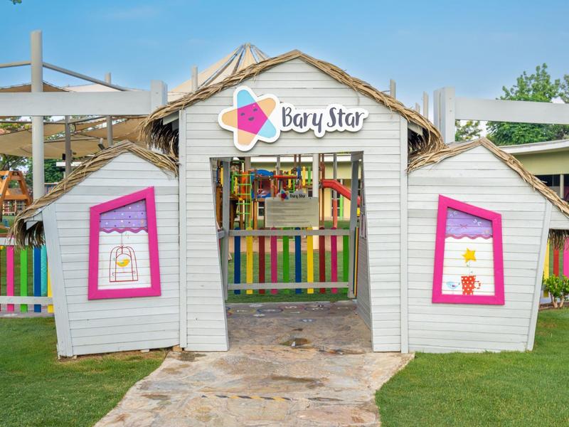 Kolorowy domek zabaw dla dzieci o nazwie Baby Star na trawniku pod niebieskim niebem.