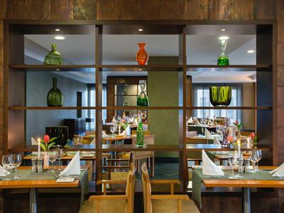 Nowoczesna część restauracyjna hotelu z drewnianymi ścianami, dekoracyjnymi butelkami i nakrytymi stołami.