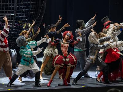 Une troupe de théâtre en costumes colorés joue une scène dramatique sur scène.