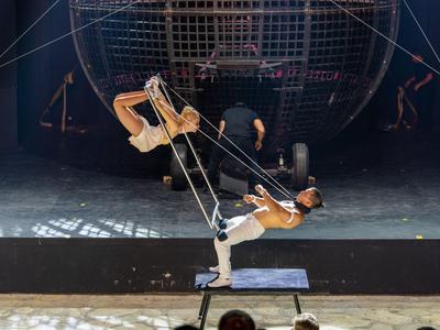Acrobate réalise un numéro de balançoire sur scène avec un grand décor sphérique