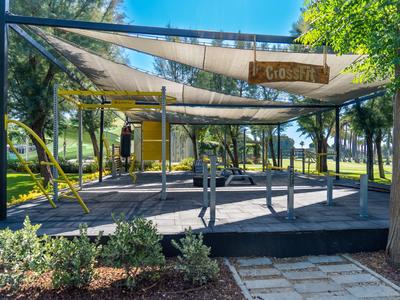 Espace fitness en plein air avec équipements d'entraînement et voiles d'ombrage dans un parc.