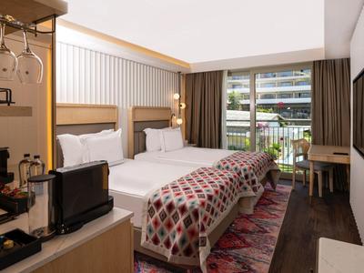 Nowoczesny pokój hotelowy z dwoma łóżkami, balkonem i widokiem na miasto.