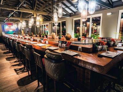 Elegancki bar z drewnianym ladą i wygodnymi stołkami w ciepło oświetlonym wnętrzu.