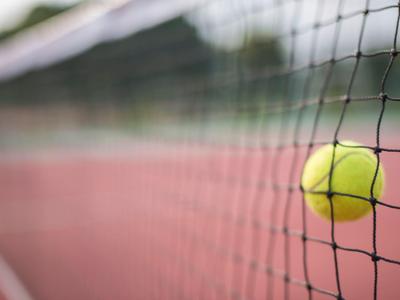 Gros plan d'une balle de tennis coincée dans le filet d'un court de tennis