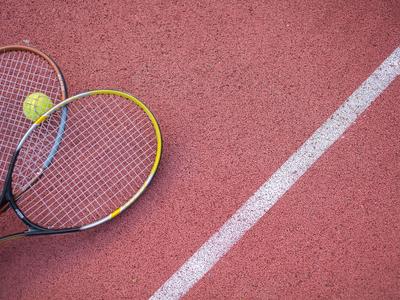 Un court de tennis avec une ligne blanche, deux raquettes de tennis et une balle jaune.