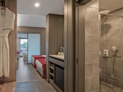 Pasillo moderno de habitación de hotel con acceso a baño y dormitorio, mobiliario cómodo y colores cálidos.