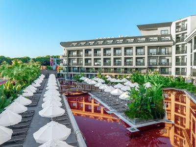 Nowoczesny hotel z basenem, leżakami i parasolami w tropikalnym otoczeniu.