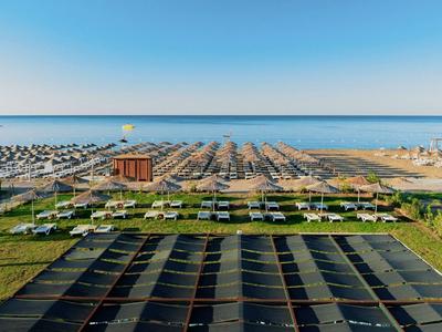 Vista aérea de un resort con piscinas y el mar al fondo, rodeado de áreas verdes.
