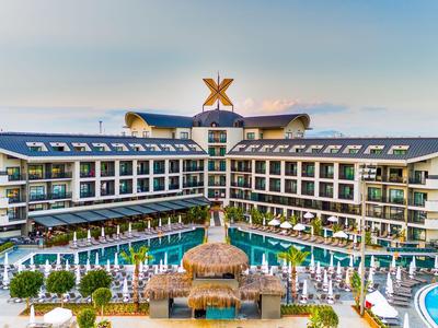 Nowoczesny kompleks hotelowy z dwoma budynkami wokół basenu i centralnej fontanny.