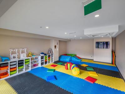 Un área de juegos infantil colorida con alfombras, cojines y estanterías llenas de juguetes en una habitación moderna.