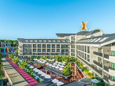 Nowoczesny hotel z tarasem na zewnątrz, leżakami i kolorowymi parasolami pod czystym niebem.