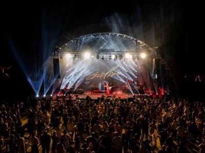 Large crowd in front of a lit stage at a nighttime concert.