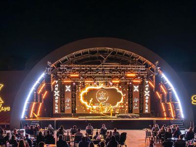 Illuminated concert stage at night with outdoor audience.