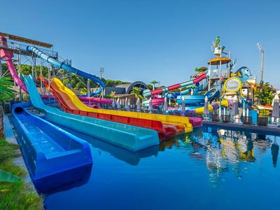 Water park with multiple colorful water slides and pool under clear blue sky.