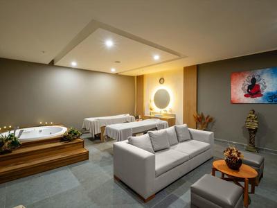 Salle de bien-être moderne avec jacuzzi, chaises longues, canapé et éclairage décoratif.